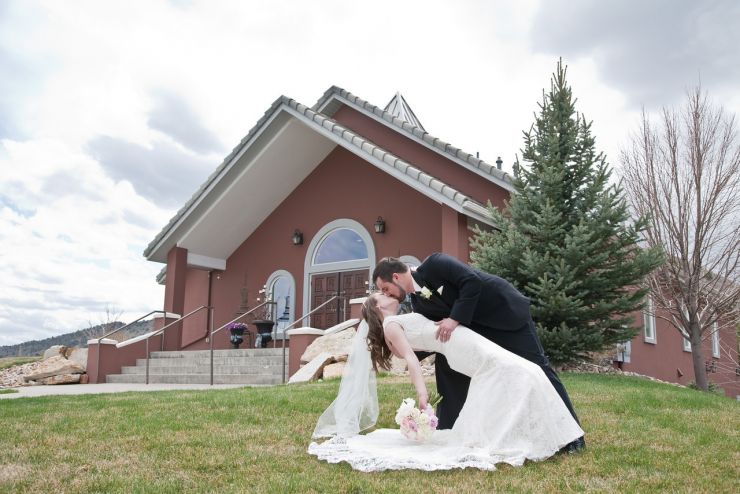 Groom kissing bride in front of wedding chapel in Colorado